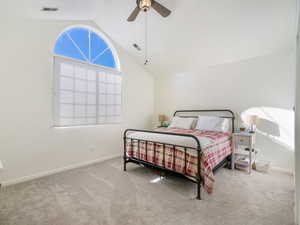Carpeted bedroom featuring a ceiling fan, vaulted ceiling, baseboards, and visible vents