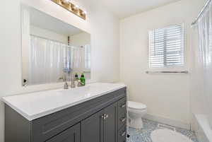 Full bath with vanity, tile patterned floors, toilet, and baseboards