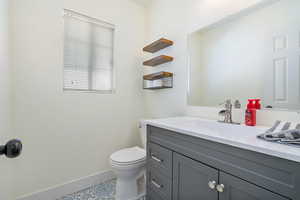 Bathroom featuring baseboards, toilet, and vanity