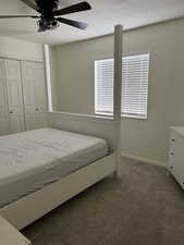 Bedroom with dark colored carpet, a closet, a ceiling fan, a textured ceiling, and baseboards