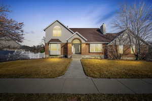 Traditional-style home featuring a front lawn, fence, brick siding, and a chimney