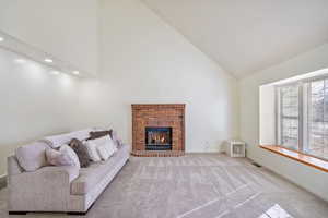 Carpeted living room with baseboards, visible vents, high vaulted ceiling, recessed lighting, and a brick fireplace