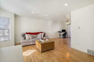 Living room featuring baseboards, visible vents, light wood-style flooring, recessed lighting, and ceiling fan