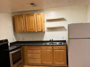 Kitchen featuring sink, electric range, light hardwood / wood-style flooring, and white fridge