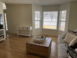 Living area with a textured ceiling, baseboards, visible vents, and light wood-style floors