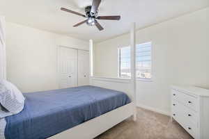 Bedroom with a closet, light colored carpet, baseboards, and a ceiling fan
