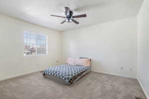 Bedroom featuring a textured ceiling, a ceiling fan, baseboards, and carpet floors