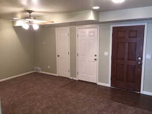 Carpeted foyer with ceiling fan