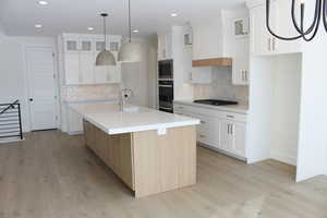 Kitchen with wall oven, a center island with sink, and white cabinets