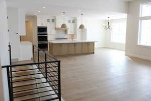 Kitchen with white cabinetry, tasteful backsplash, light wood-type flooring, a large island with sink, and stainless steel appliances