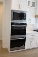 Details with black appliances, light hardwood / wood-style floors, decorative backsplash, and white cabinets