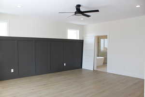 Unfurnished bedroom featuring multiple windows, light hardwood / wood-style flooring, ceiling fan, and ensuite bathroom