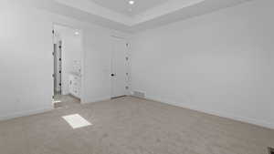 Unfurnished bedroom with connected bathroom and light colored carpet