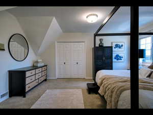 Carpeted bedroom with vaulted ceiling and a closet