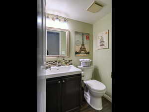 Bathroom featuring tasteful backsplash, hardwood / wood-style floors, vanity, and toilet