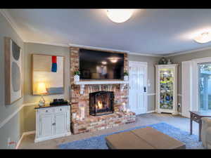 Living room with crown molding, light colored carpet, and a brick fireplace