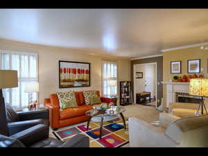 Living room with crown molding, carpet flooring, a tile fireplace, and a wealth of natural light