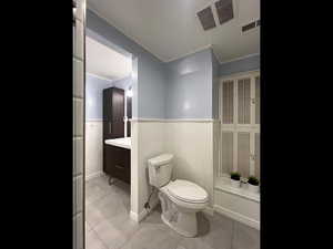 Bathroom with vanity, tile patterned floors, ornamental molding, and toilet