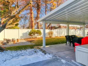 Snow covered patio featuring a fire pit and a lawn