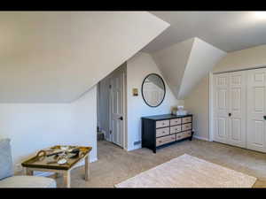 Bedroom with vaulted ceiling, light colored carpet, and a closet