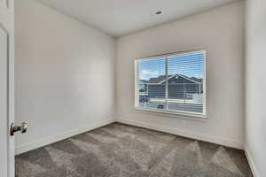 Carpeted spare room featuring baseboards