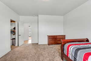 Bedroom with light colored carpet and a closet