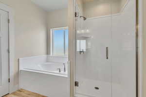 Bathroom with a shower stall, a bath, and wood finished floors