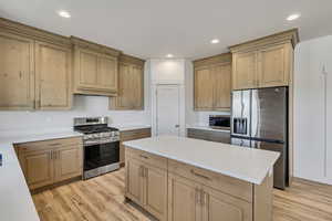 Kitchen with appliances with stainless steel finishes, light wood-style flooring, recessed lighting, a center island, and light brown cabinets
