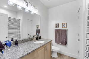 Bathroom with hardwood / wood-style flooring, vanity, and toilet