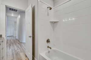 Bathroom with shower / washtub combination and wood finished floors
