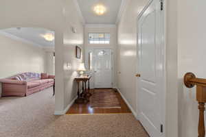 Carpeted entrance foyer featuring crown molding