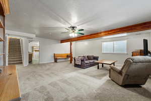 Living room featuring ceiling fan, light colored carpet, and a textured ceiling