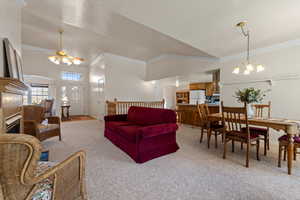 Living room with light carpet, high vaulted ceiling, ceiling fan with notable chandelier, and ornamental molding