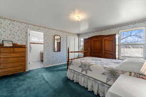 Bedroom featuring connected bathroom, a textured ceiling, and dark carpet