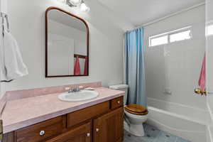 Full bathroom with vanity, tile patterned floors, shower / bath combination with curtain, and toilet