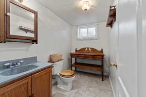 Bathroom featuring vanity, tile patterned floors, a textured ceiling, and toilet