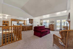 Carpeted living room with lofted ceiling and a notable chandelier