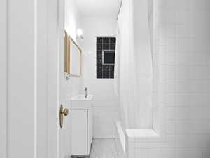 Bathroom with tile patterned flooring, vanity, tile walls, and shower / bath combination with curtain