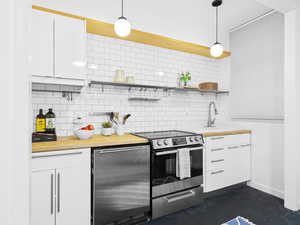 Kitchen with pendant lighting, sink, stainless steel electric range, and white cabinets