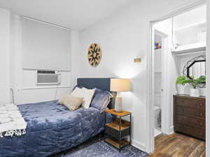 Bedroom featuring cooling unit, ensuite bathroom, and dark hardwood / wood-style floors