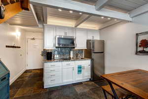 Kitchen featuring stainless steel appliances, granite counters, wood ceiling, and beam ceiling