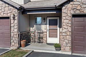 Doorway to property with a garage and a porch