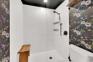 Bathroom featuring tiled shower and toilet