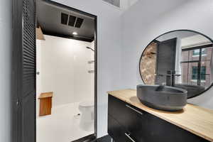 Bathroom featuring tile patterned flooring, vanity, tiled shower, and toilet