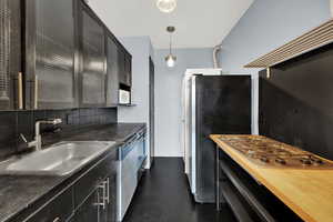 Kitchen with pendant lighting, sink, butcher block countertops, stainless steel appliances, and tasteful backsplash