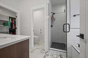 Bathroom featuring vanity, toilet, and a shower with door