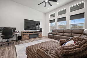 Living room featuring wood-type flooring, ceiling fan, and a high ceiling