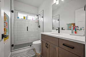 Bathroom featuring tile patterned flooring, vanity, walk in shower, and toilet