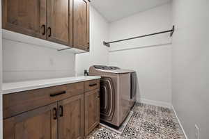 Washroom featuring light tile patterned floors, washer and clothes dryer, and cabinets