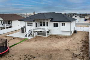 Rear view of property with a trampoline, central AC, and a patio area